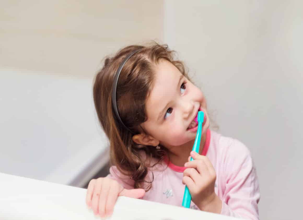 young girl brushing her teeth at home